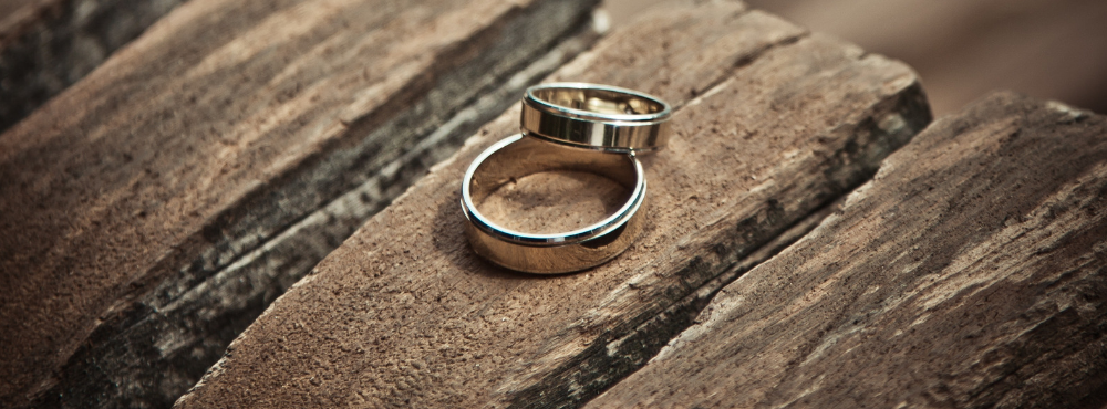 Two gold rings on a weathered rustic wooden table.